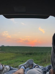 two people are sitting in the back of a truck with their feet on the ground