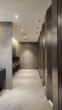 a long hallway with several urinals and lights on either side of the wall