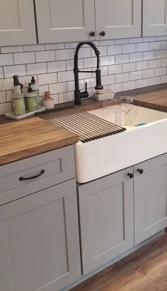 a kitchen with white cabinets and wooden counter tops, an apron style sink and black faucet