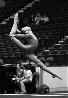 a woman in purple leotard doing a trick on the floor with her hands