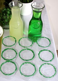 several green glass vases sitting on top of a white table covered in plastic circles