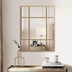 a mirror hanging on the wall above a dresser in a room with white walls and wooden floors