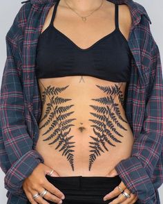 a woman's stomach with a fern tattoo on her belly and the bottom part of her body