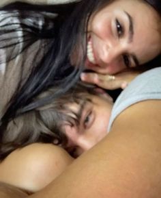 two women laying in bed with their heads on each other