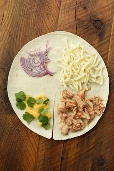 a tortilla with shredded cheese, meat and vegetables on it sitting on a wooden table