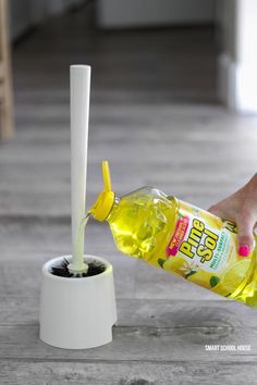 a person pouring oil into a container with a toothbrush in it and a tube sticking out of the top