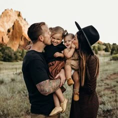 a man and woman are holding two small children in their arms while they look at each other