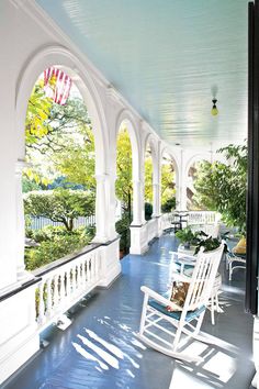 an iphone photo of a porch with rocking chairs and potted plants on the balcony