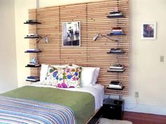 a bed sitting in a bedroom next to a wall mounted book shelf with pictures on it