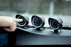 three speedometers sitting on the dashboard of a car