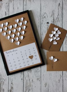 a calendar with paper hearts attached to it and two small envelopes next to it