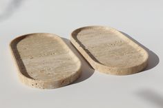 two wooden trays sitting next to each other on a white counter top with shadows