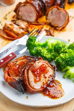 meat, broccoli and carrots on a white plate with a red knife