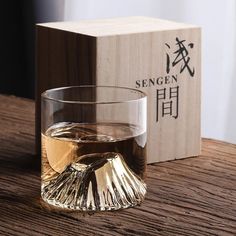 a glass filled with liquid sitting on top of a wooden table next to a box