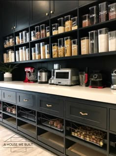 a kitchen counter with lots of food in containers on the wall and shelves above it