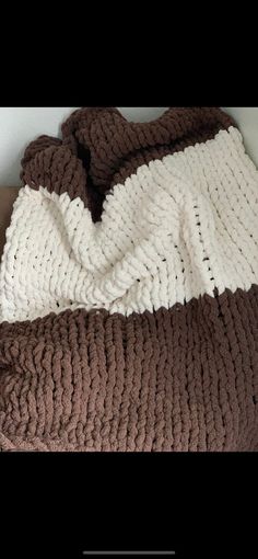 a brown and white crocheted blanket on top of a bed next to a pillow