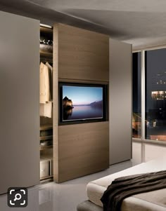 a bedroom with a bed, television and closets in it's corner by the window