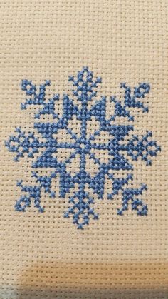 a cross stitch snowflake is shown in blue