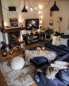 a living room filled with lots of furniture and lights hanging from the ceiling above it