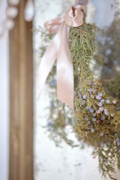 a close up of a wreath hanging on a door with a ribbon and bow around it