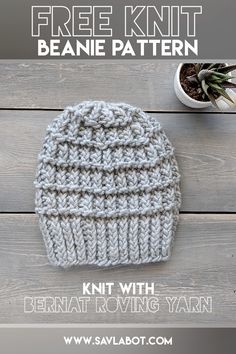 a knitted hat sitting on top of a wooden table next to a potted plant