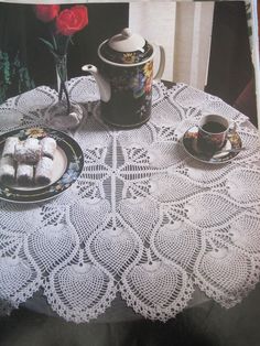 a table topped with two plates of pastries and a vase filled with red roses