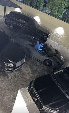 two cars are parked in an empty parking garage, one is black and the other is silver