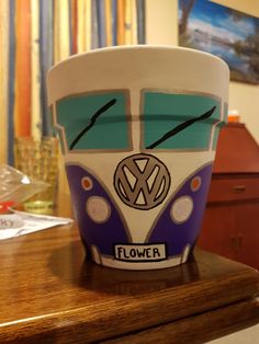 a cup that is sitting on top of a wooden table with the word flower painted on it