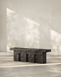 a black bench sitting in the middle of a room next to a wall with shadows on it