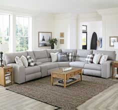 a living room with a large sectional couch and coffee table in front of the window