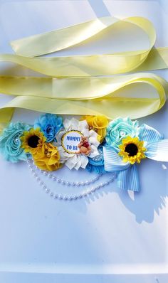 flowers and ribbons are arranged on a white surface with blue, yellow, and white streamers