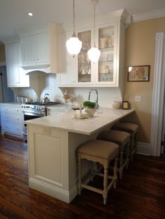 a large kitchen with white cabinets and counter tops, along with an island in the middle