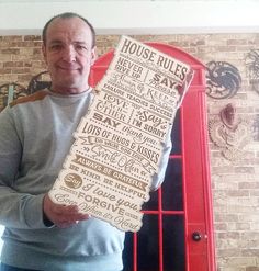 a man holding up a large piece of paper with words on it in front of a brick wall