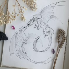 a drawing of two dragon sitting on top of a table next to flowers and plants