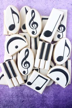 cookies decorated with music notes and musical instruments are on a purple tablecloth in front of a purple background