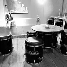 a black and white photo of some drums in a room with stools on the floor