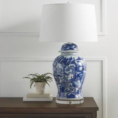 a blue and white vase sitting on top of a wooden table next to a lamp