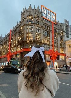 a woman standing in front of a large building with lights on it's sides