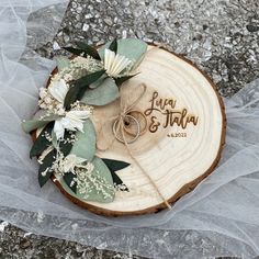 the wedding rings are placed on top of a tree slice with flowers and greenery