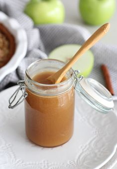 an apple pie in a glass jar with a wooden spoon on a plate next to it