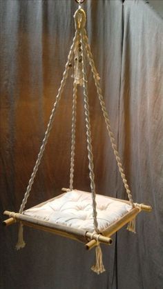 a hanging chair made out of rope and wood with a cushion on it's back