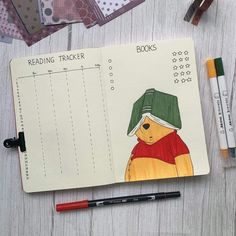 an open notebook with a drawing of a teddy bear on it and some markers next to it