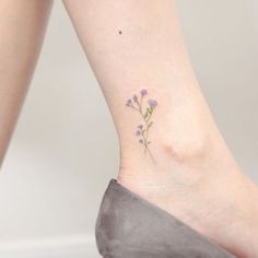 a small flower tattoo on the ankle that is sitting on a woman's foot