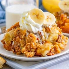 a close up of a plate of food with bananas and whipped cream on it next to a glass of milk