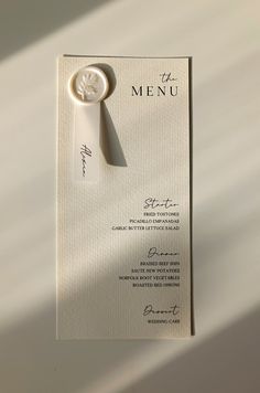 a white menu card with a wax stamp on it's side and a button at the top