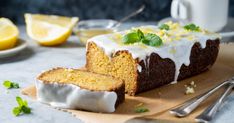 a loaf of lemon cake sitting on top of a cutting board next to sliced lemons