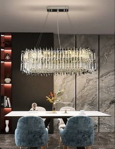 an elegant dining room with modern chandelier and blue chairs in front of the table