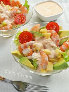 two bowls filled with salad and dressing on top of a white table cloth next to silverware