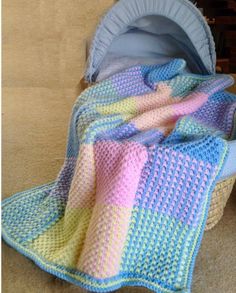 a crocheted blanket sitting on the floor next to a baby stroller with it's cover pulled up