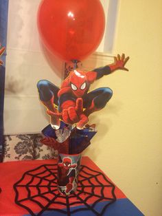 a spiderman centerpiece on a table next to a red balloon and some other decorations